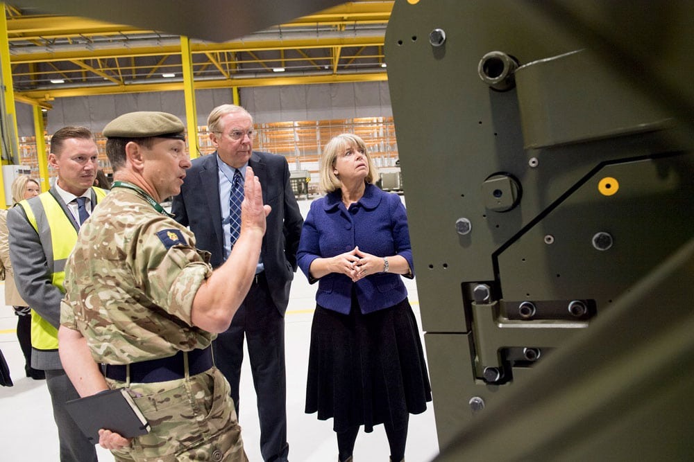 A female government minister being shown an armoured vehicle