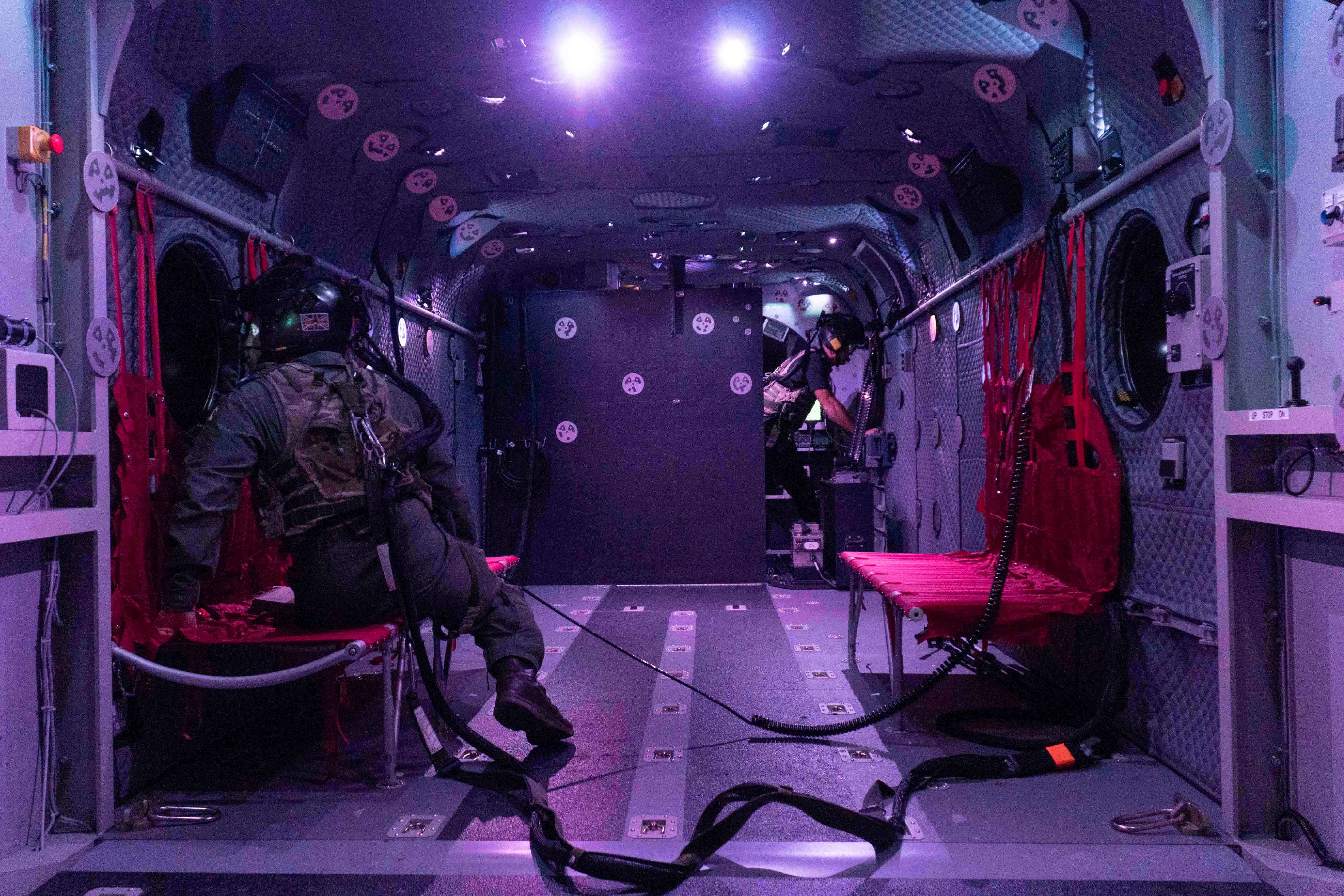 Two soldiers sit in the back of a helicopter