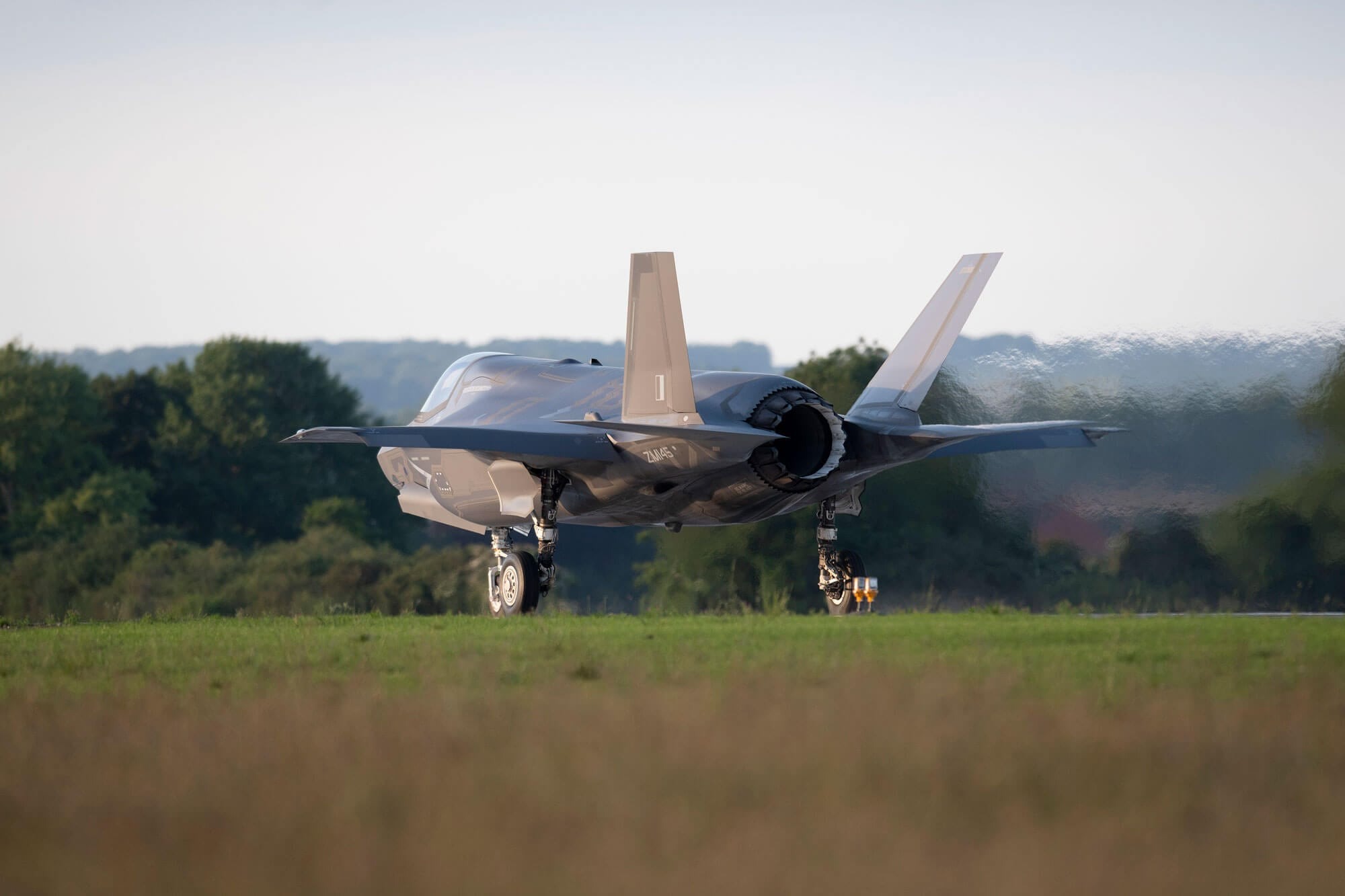 Large grey fighter jet on a runway from behind