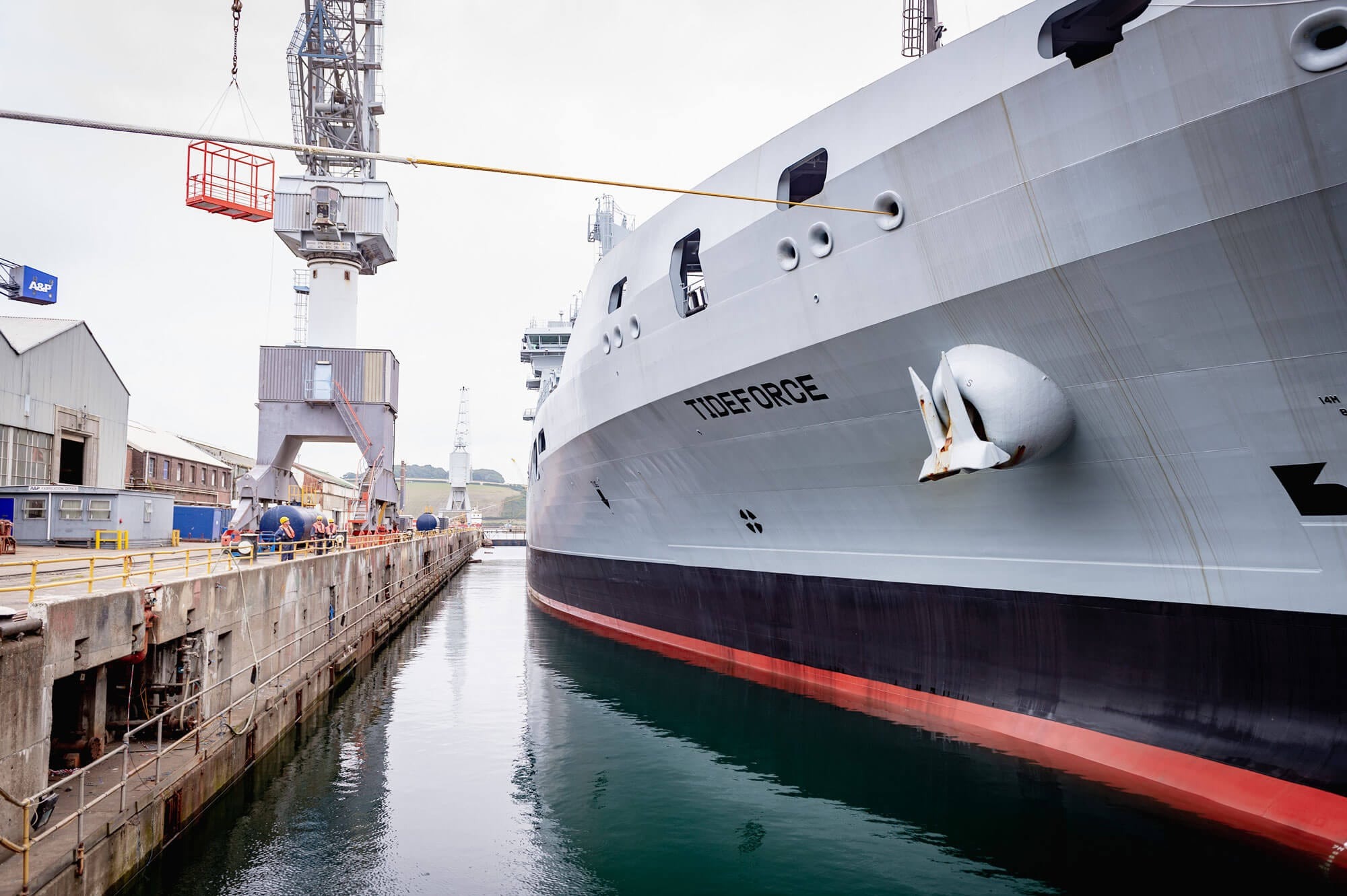 A long grey ship in still harbour waters