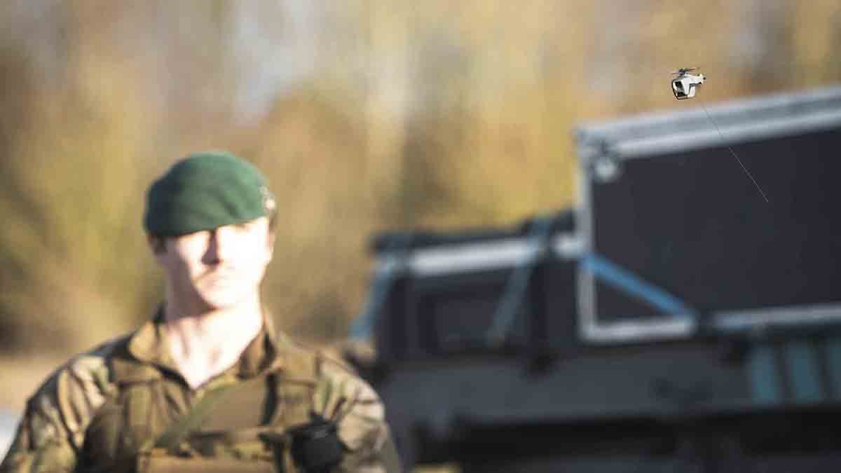 A solider smiles in the sunshine stood beside a tank