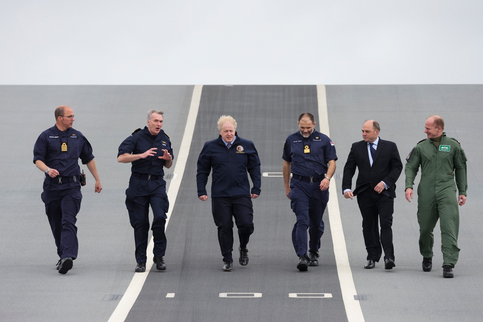 Prime Minister Boris Johnson and Defence Secretary Ben Wallace walk along the flight deck of HMS Queen Elizabeth with senior members of the Royal Navy