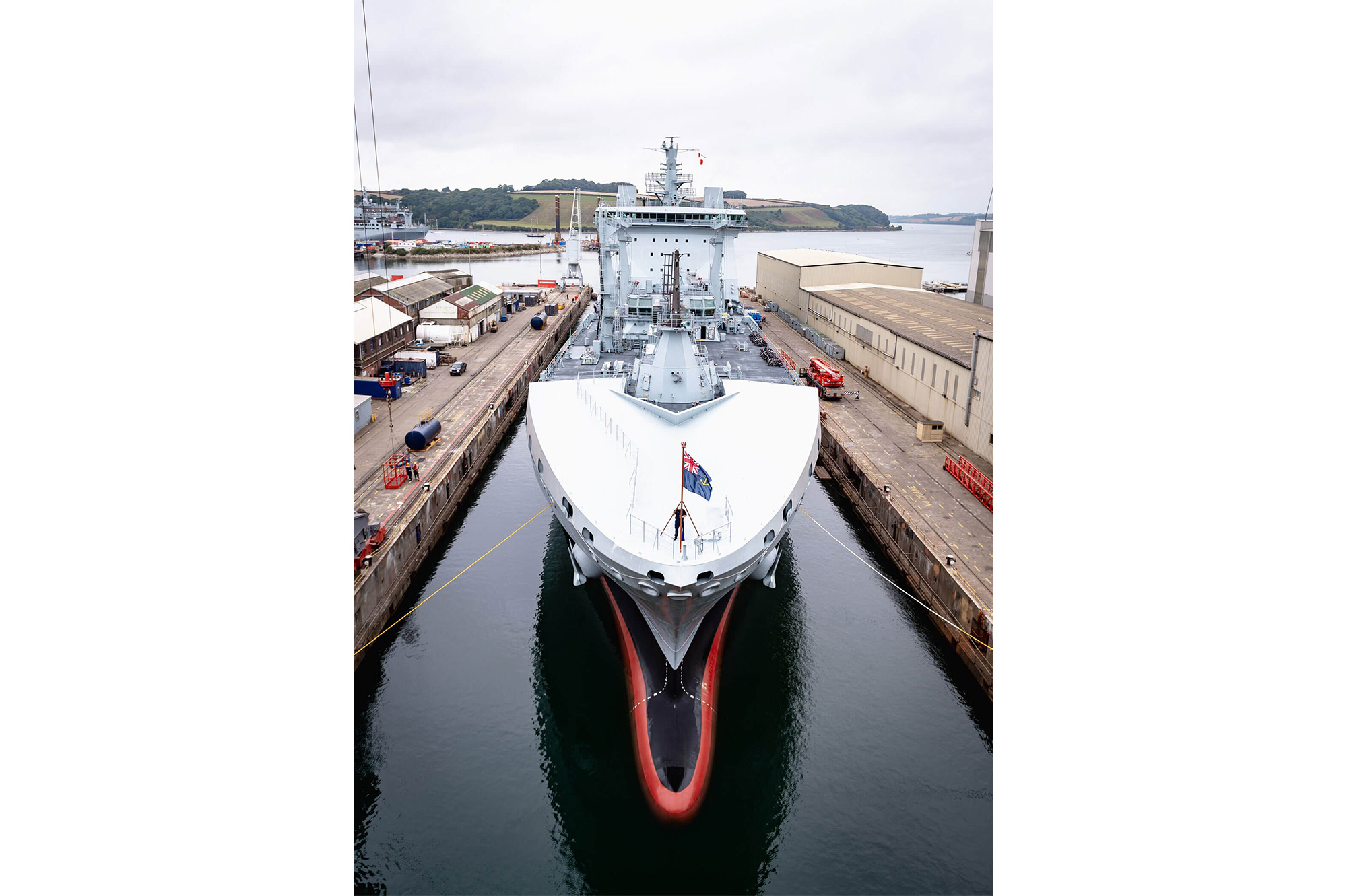 A long grey ship in still harbour waters