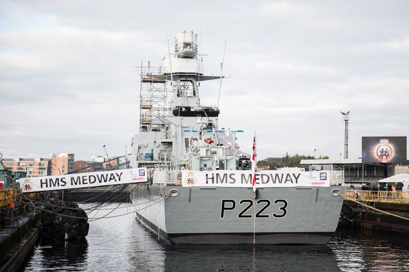 A grey navy ship carrying a banner with HMS Medway written on it