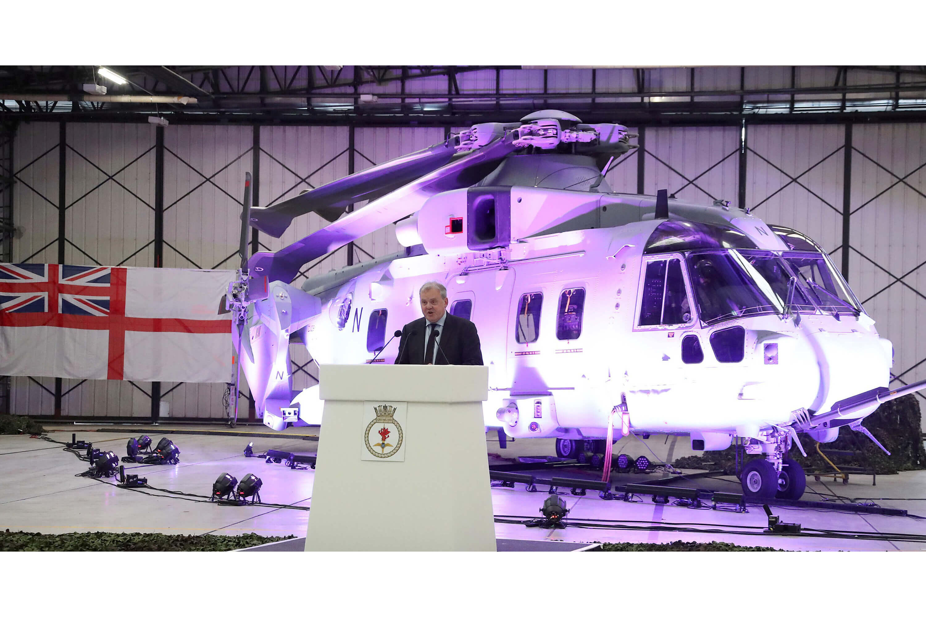 A helicopter lit up by a purple light in a hangar