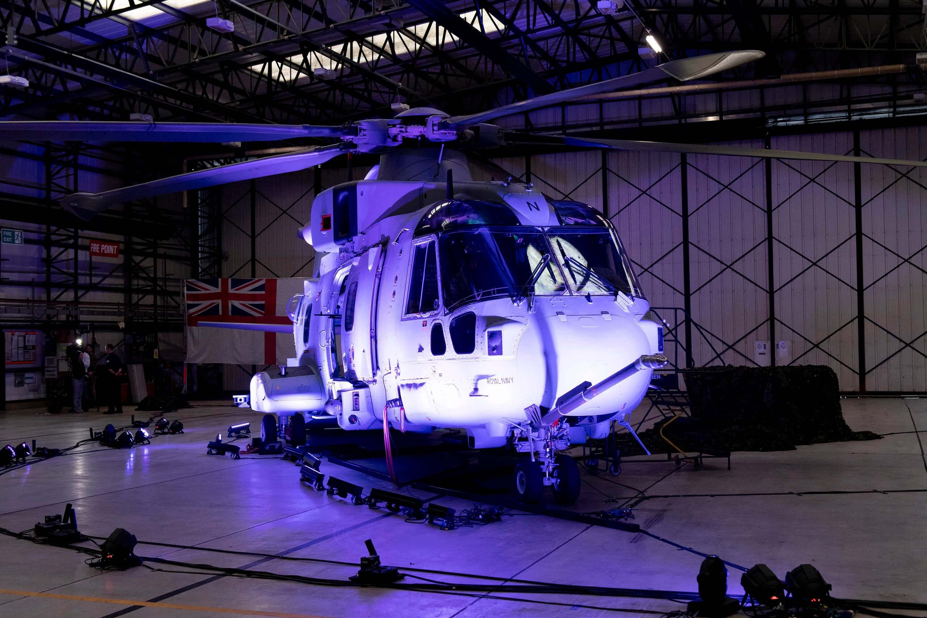 A helicopter lit up by a purple light in a hangar