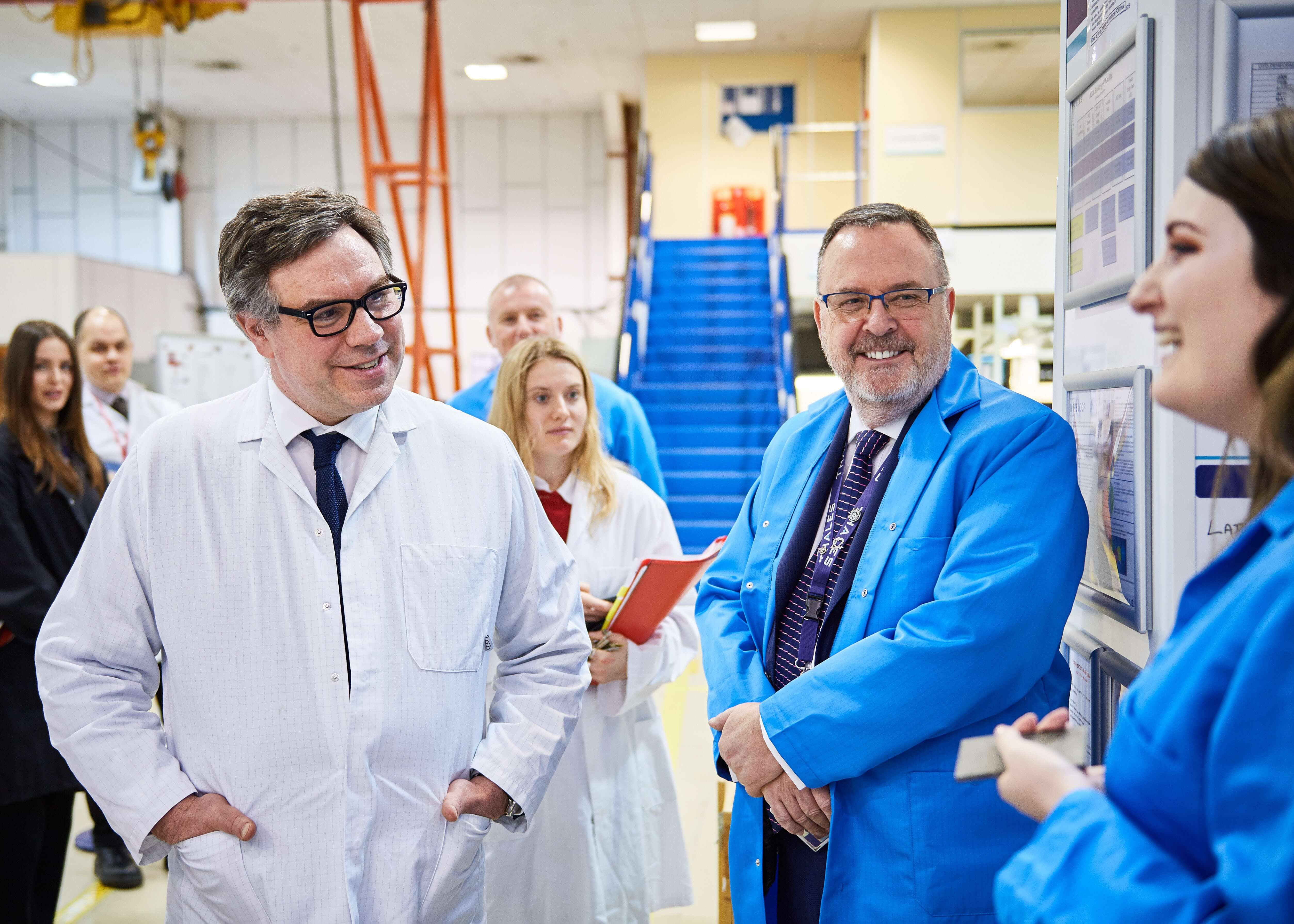 A male government minister meets people in blue protective clothing