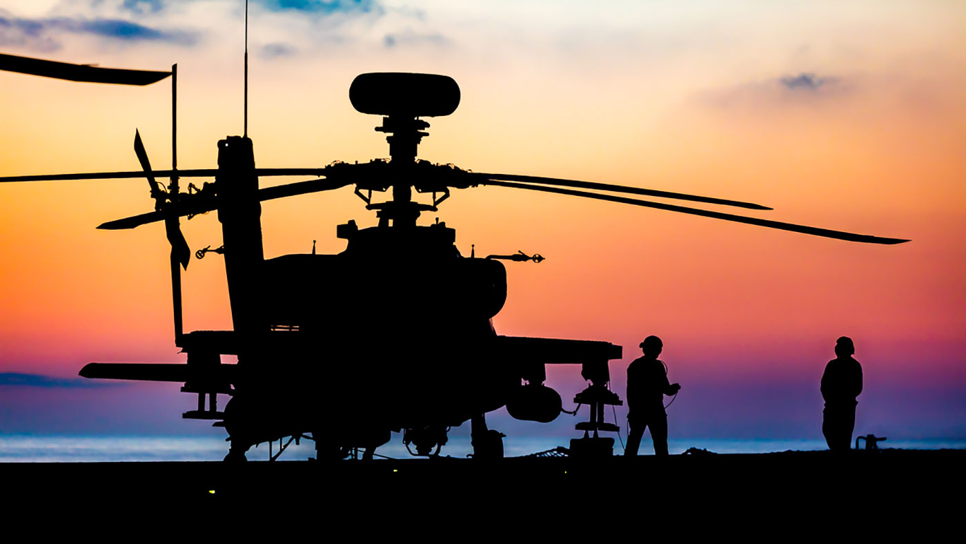 Silhouette of military helicopter with two people of the right with a red and blue sky