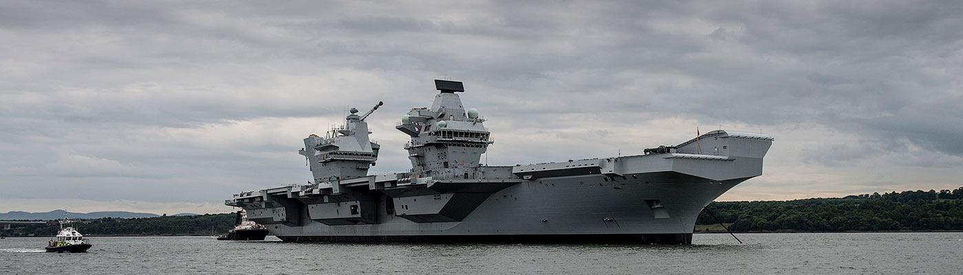 large grey ship anchored with two small boats alongside