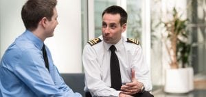 A naval officer interviews a young man in a blue shirt