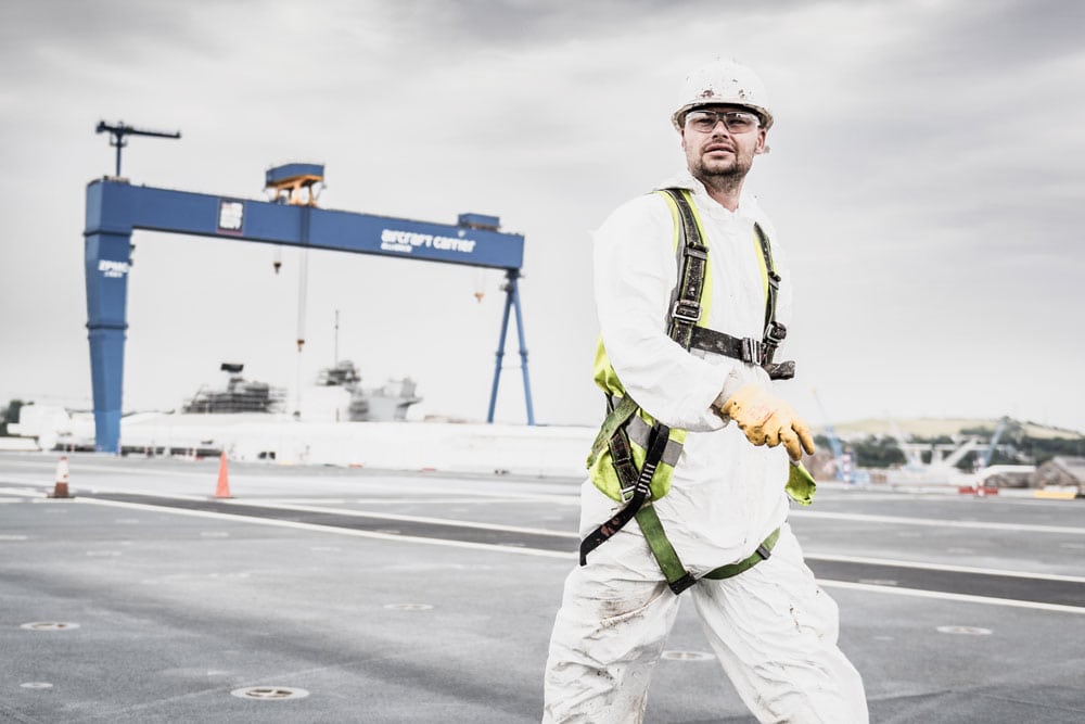 Worker walks in front of huge blue dockyard crane