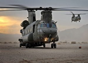 Two military helicopters take off at sunset