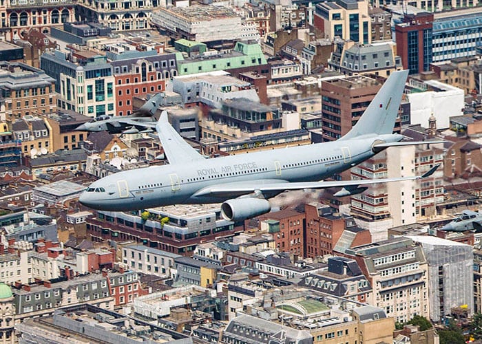 A grey military plane flies over the city of london