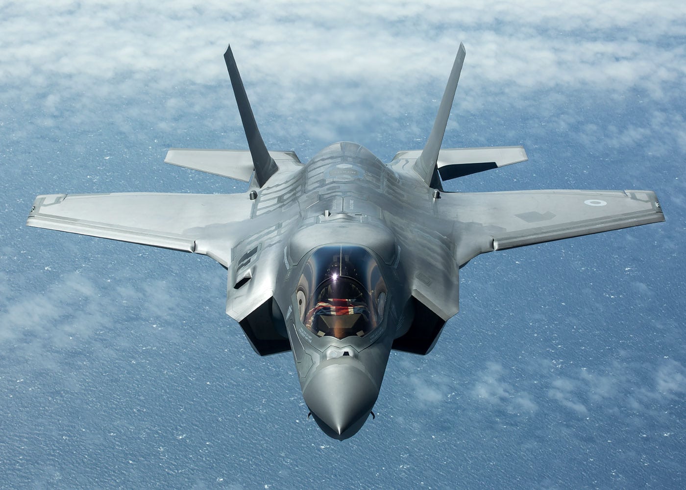 large grey fighter jet in the sky, seen from above