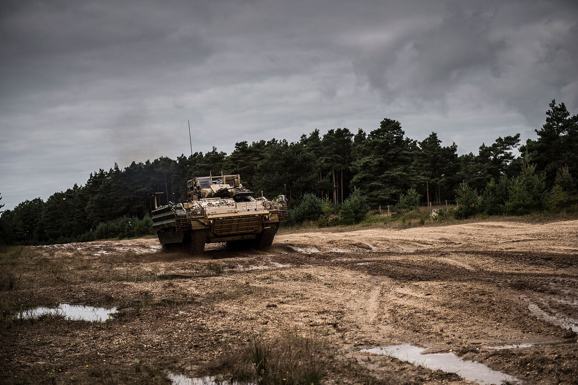 A military tank driving over mud