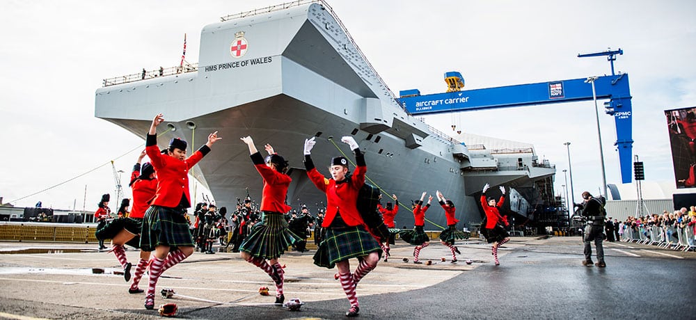 Scottish dancers perform in front of the navy aircraft carrier