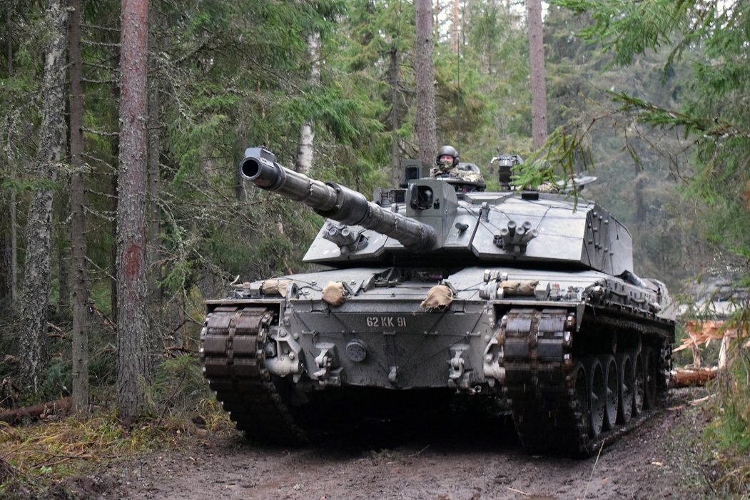 Pictured is a Challenger 2 tank, breaching an obstacle formed from felled trees during a training exercise.