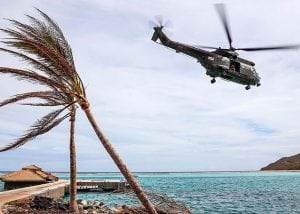 helicopter flies over Caribbean beach after hurricane