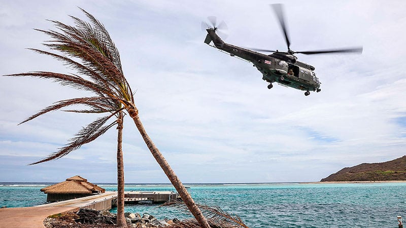 helicopter flies over Caribbean beach after hurricane