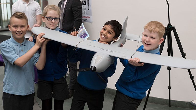 four children pose with a drone