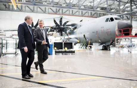 Large military plane in hangar, with men walking in front