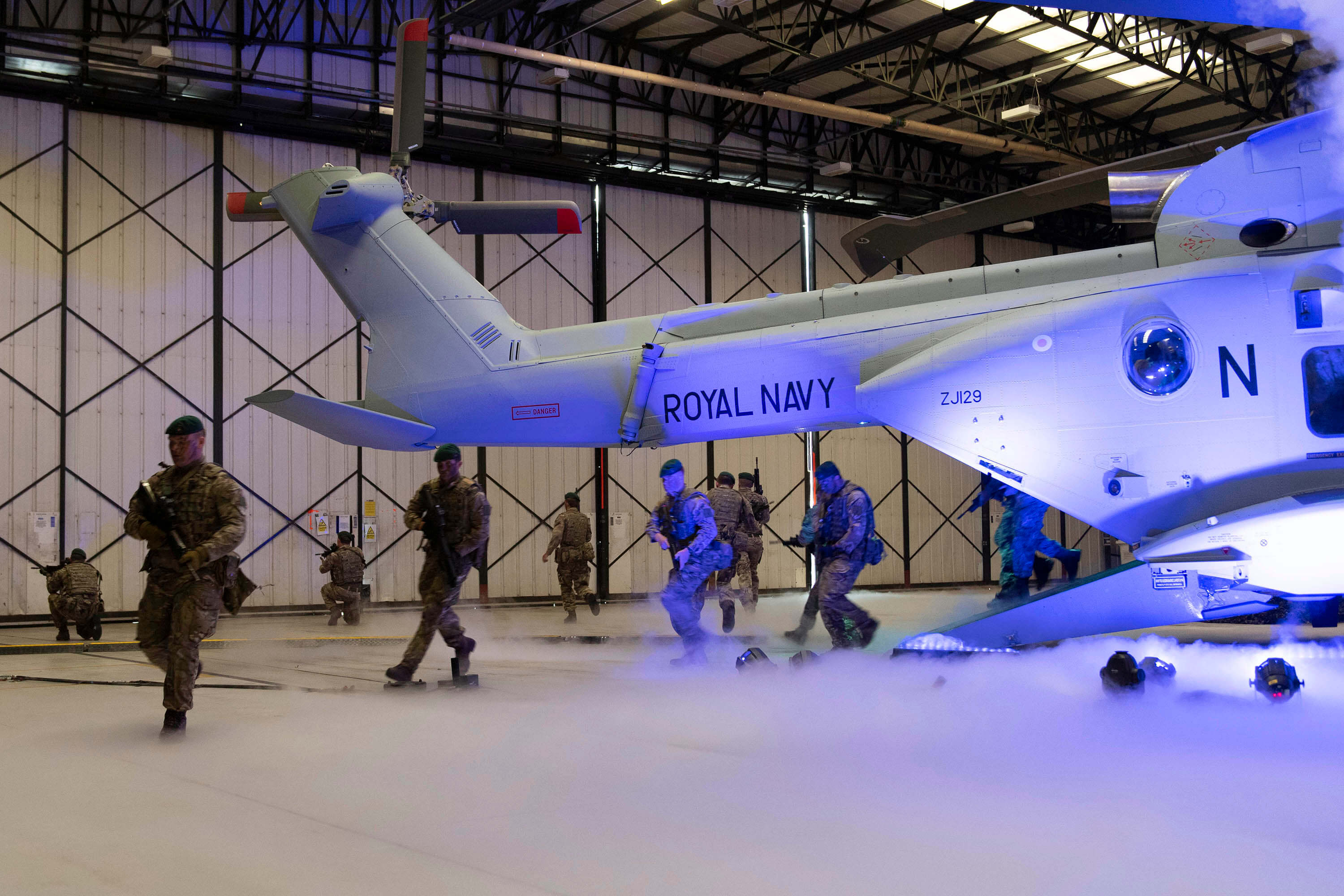 A helicopter in a hangar with soliders coming out of the rear