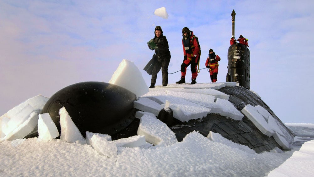 people stand on top of a submarine that has broken through the arctic ice