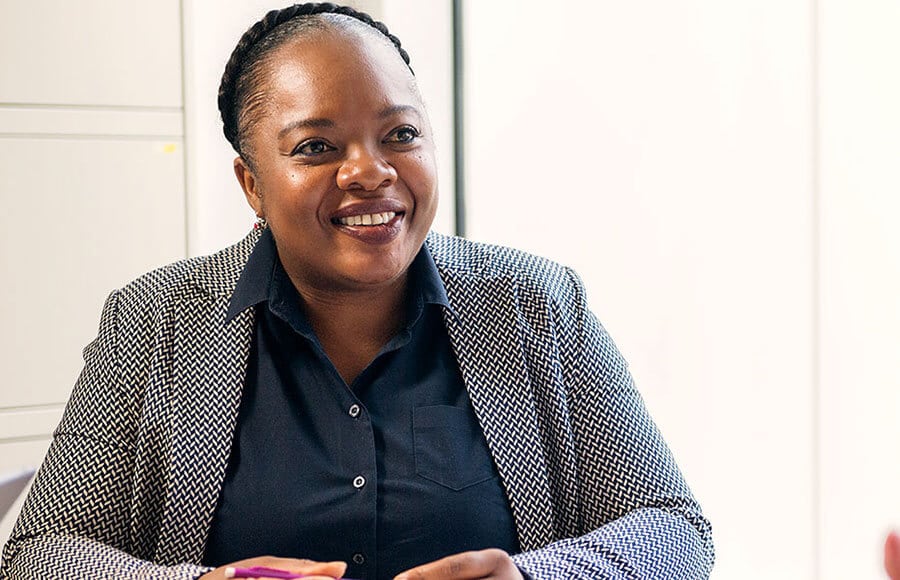 A woman in a grey smart jacket and blue shirt smiles