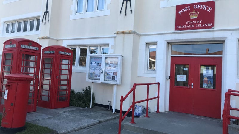 A white building with red doors and two red phone boxes stood outside