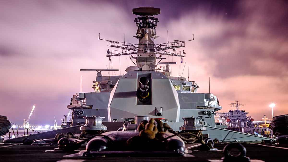 A large grey navy ship's deck with a purple sky in the background