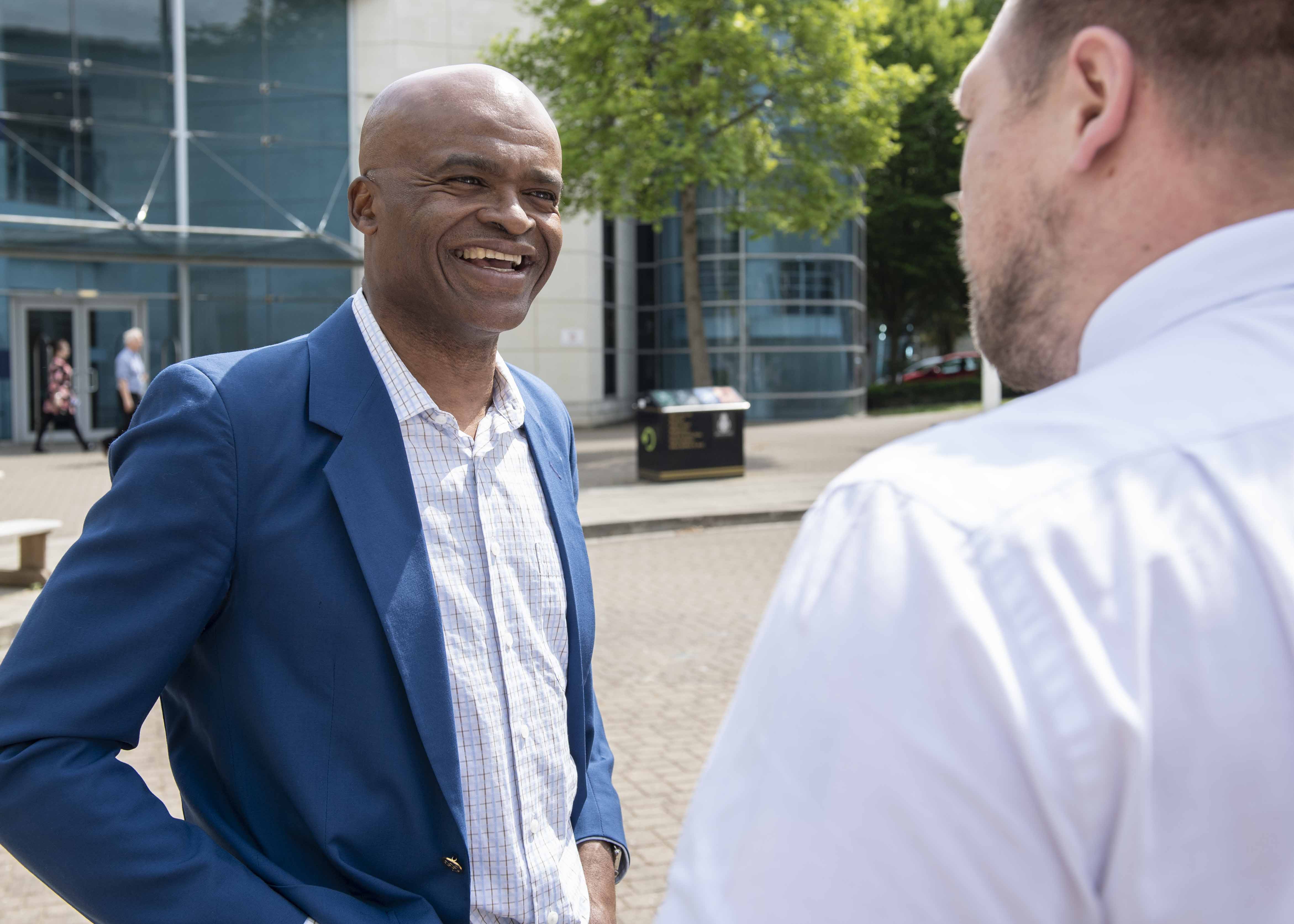 A man smiles at another man during a conversation