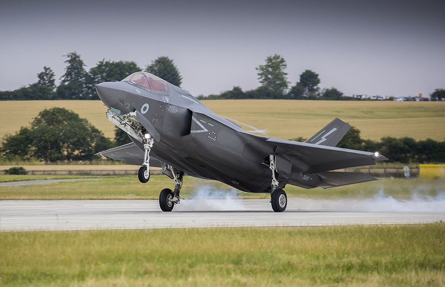 A grey fighter jet takes off from a runway