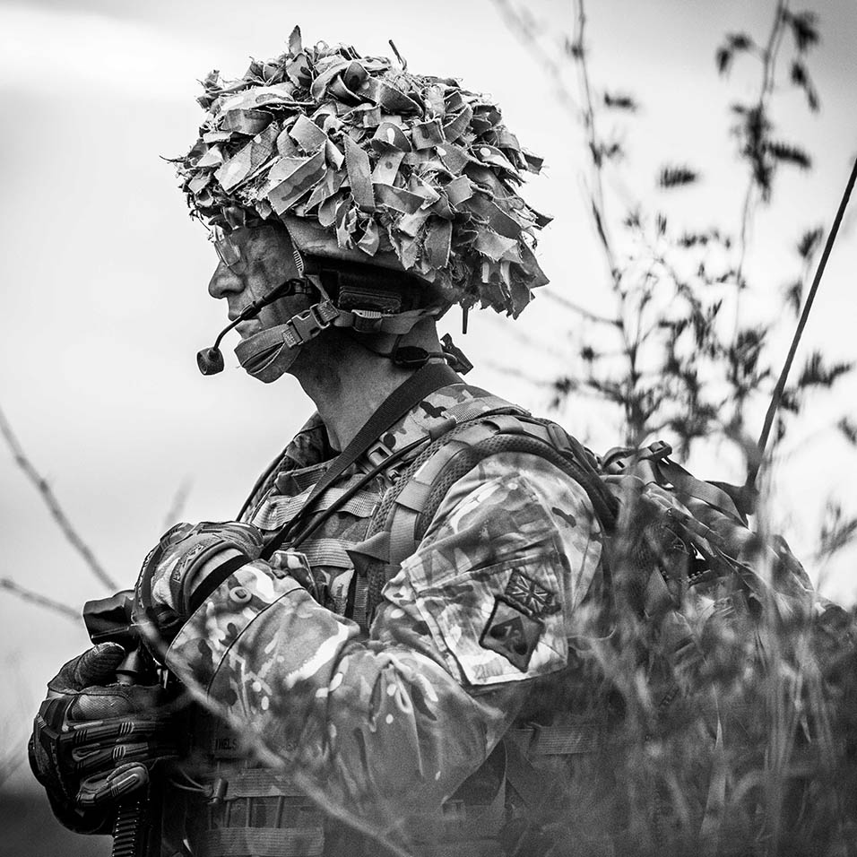 A black and white photo of a solider in a camouflage hat