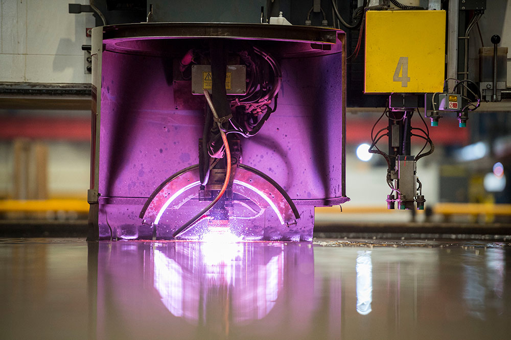 A laser glowing purple as it cuts through steel