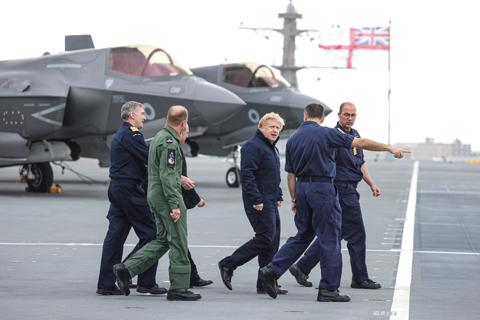 Prime Minister Boris Johnson and Defence Secretary Ben Wallace walk along the flight deck of HMS Queen Elizabeth with senior members of the Royal Navy