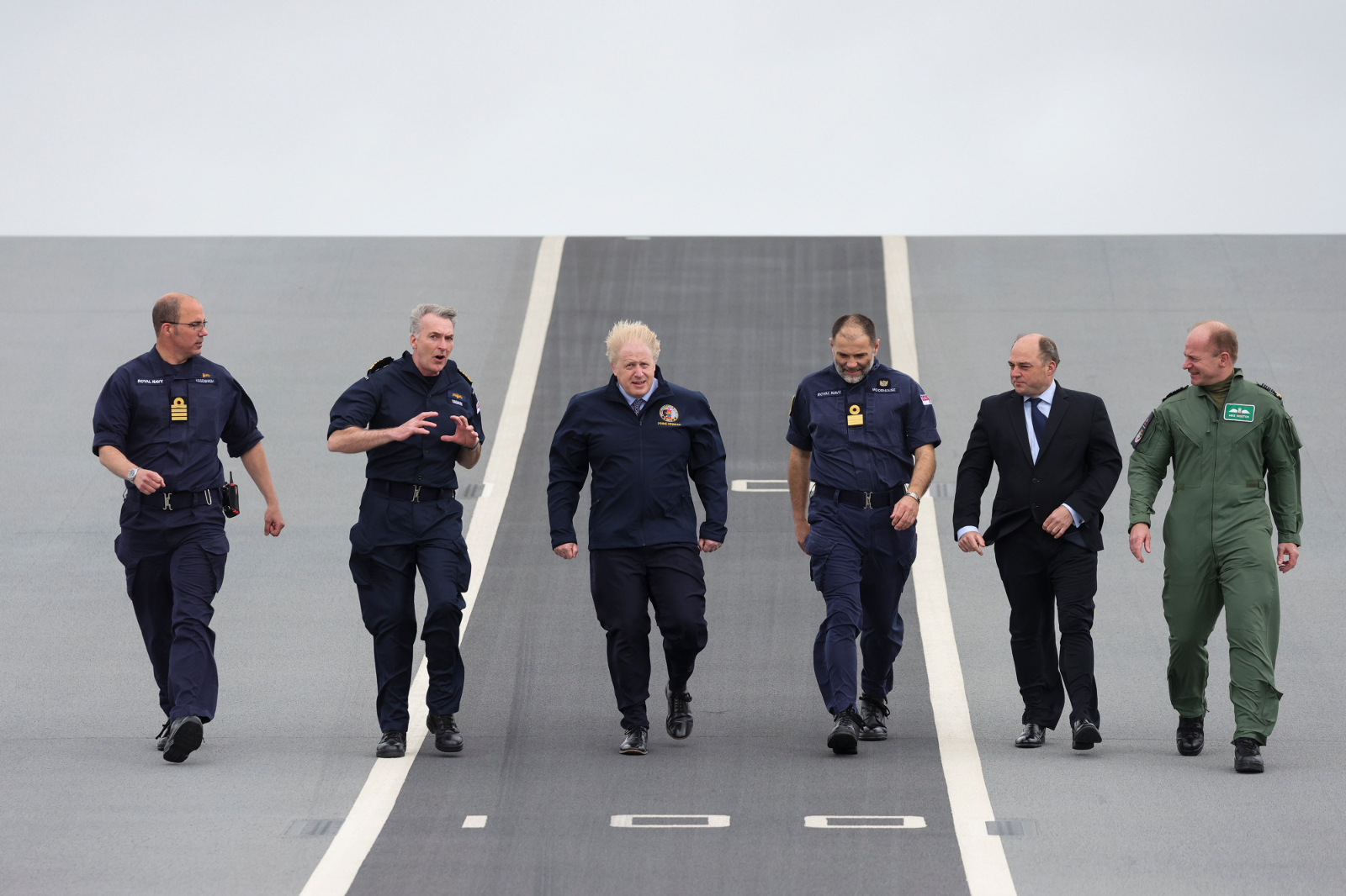 Prime Minister Boris Johnson and Defence Secretary Ben Wallace walk along the flight deck of HMS Queen Elizabeth with senior members of the Royal Navy