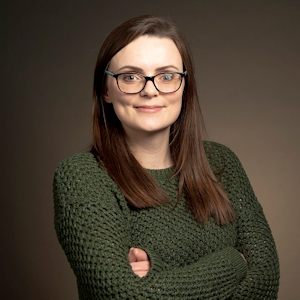 Safety Engineer Sophie in dark green jumper with arms folded facing cameradark gre