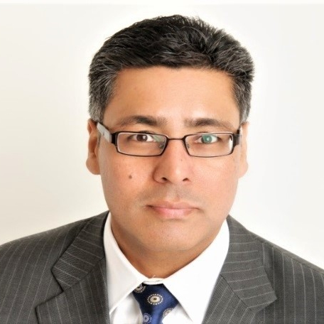 headshot of Commercial Integration Manager Amarjit in glasses grey pin stripe suit, white shirt and blue tie