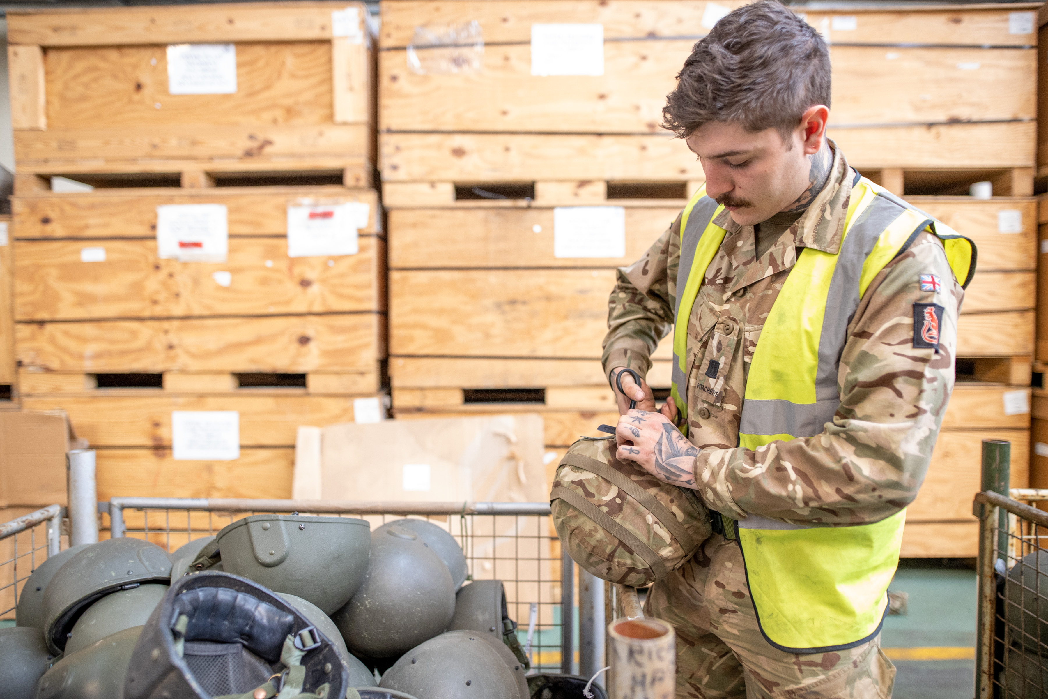 A soldier from 2nd Battalion The Royal Anglian Regiment cuts off the ties of the helmet to prepare it for packaging at MOD Donnington.