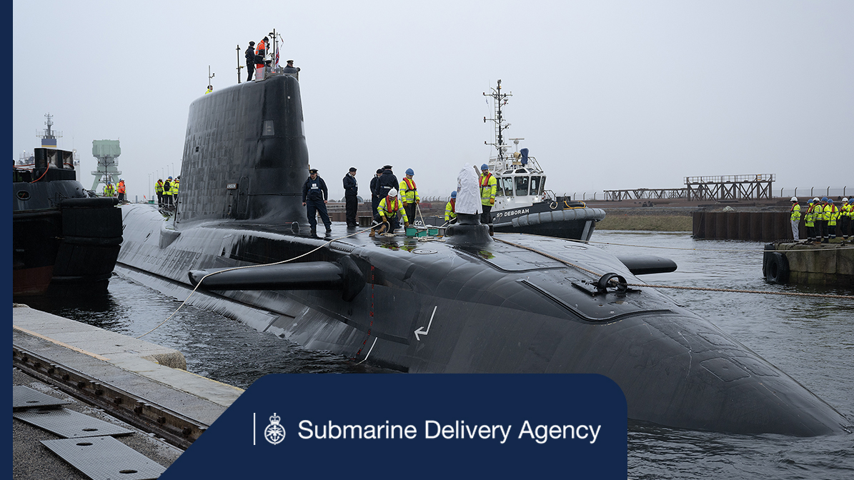 A submarine in the water with crew standing on top, alongside a boat