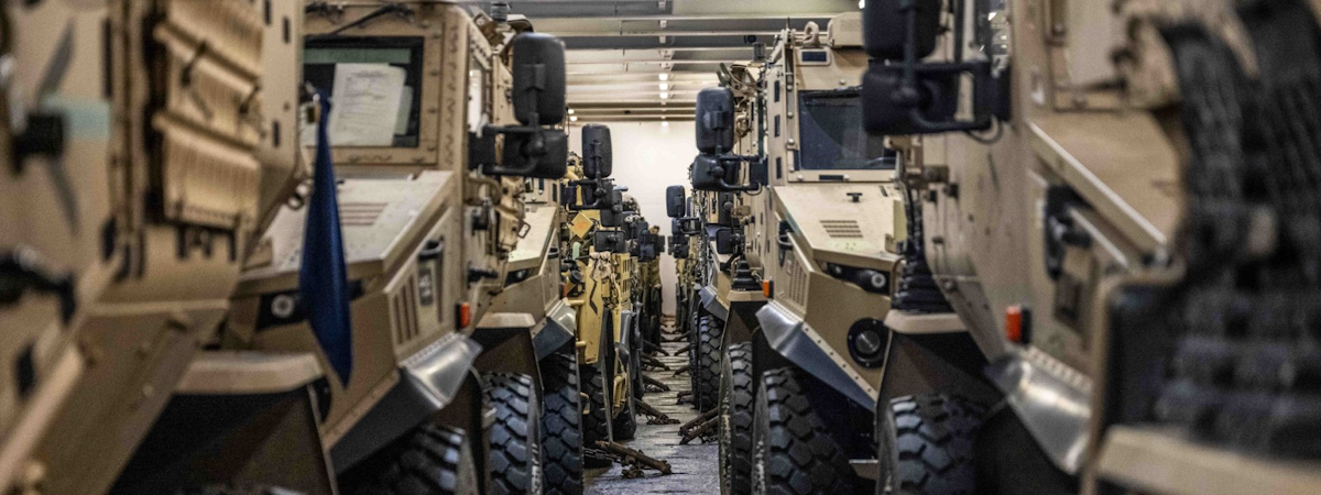 Looking down the middle of two columns of armoured vehicles secured to the floor in a transporter
