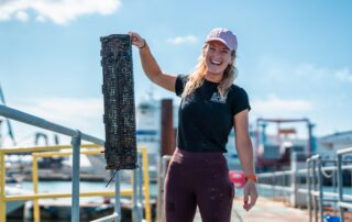 Harriet Rushton from the DE&S SALMO Wrecks team holding up an oyster cage