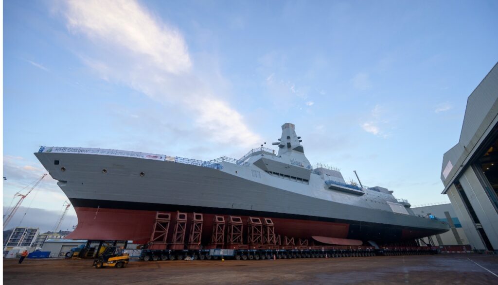 Type 26 Frigate HMS Cardiff being wheeled along dockyard towards the water.