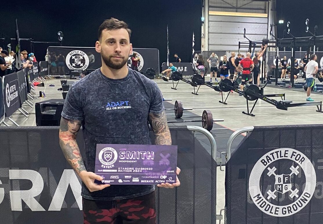 Liam Smith holding an award with row of cross trainers behind him