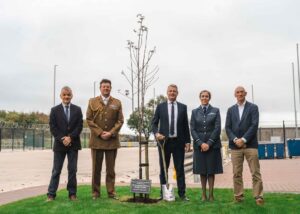 A group of people standing by a newly planted tree