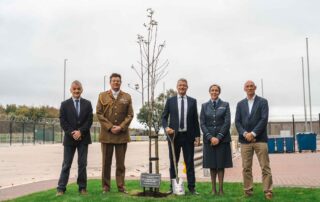 A group of people standing by a newly planted tree
