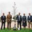 A group of people standing by a newly planted tree