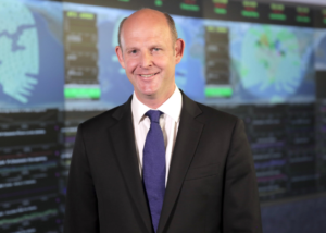 Rupert Pearce standing in front of computer screens
