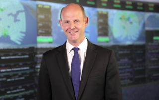 Rupert Pearce standing in front of computer screens