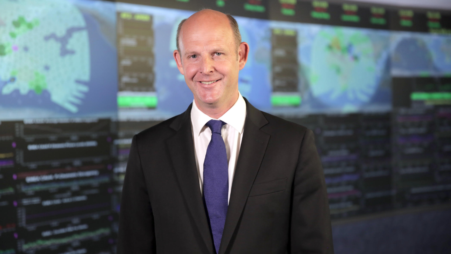 Rupert Pearce standing in front of computer screens